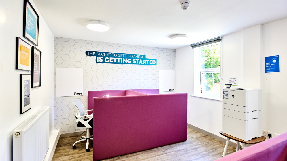 A room with study desks with partitions and a printer